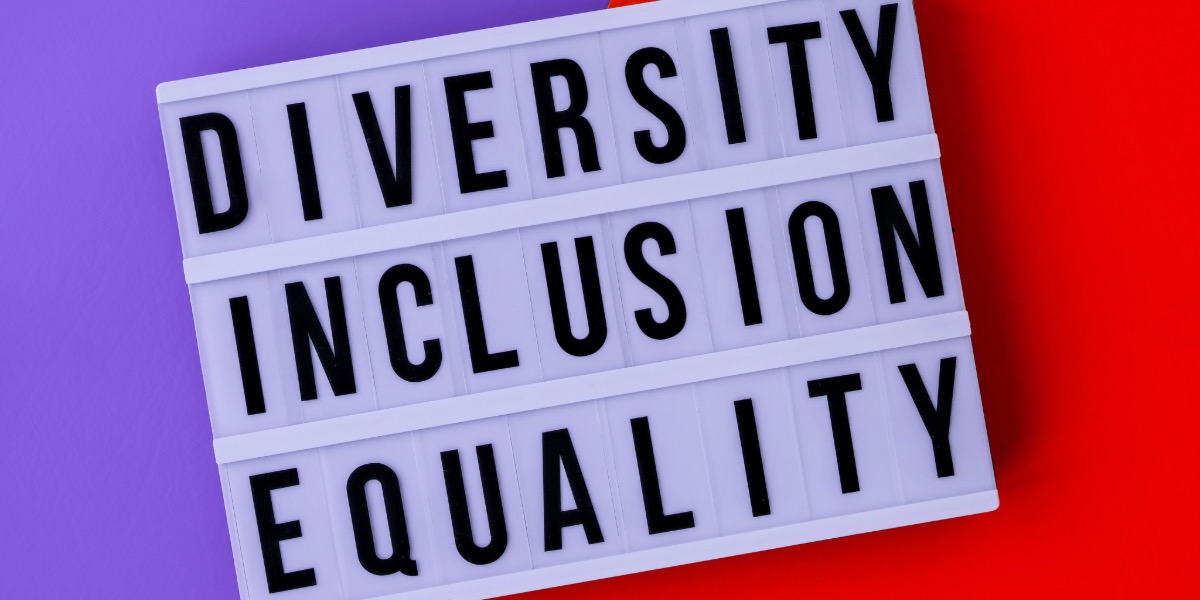 Bold black text on a white lightbox spells out 'Diversity, Equity, Inclusion' against a vibrant split background of purple and red—symbolizing unity through contrast and the core values of social justice and representation.
