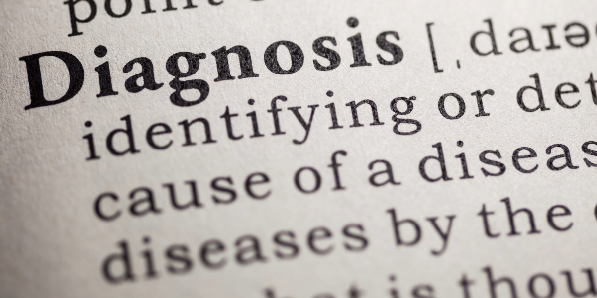 Close-up image of a dictionary page highlighting the word "Diagnosis" in bold, followed by its definition, which includes the phrase "identifying or determining the cause of a disease." The text is sharply focused on the definition, while the surrounding words fade slightly out of focus.