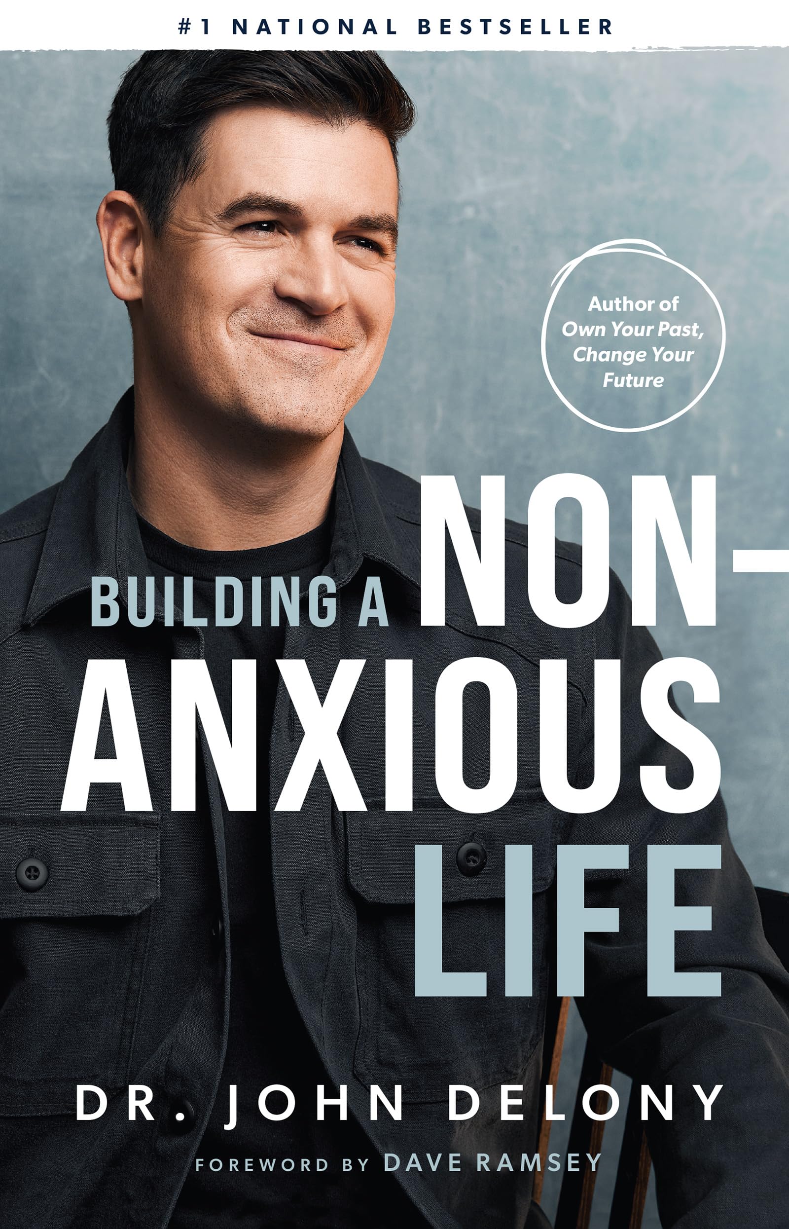 Version 100 – To Speak Online Book cover featuring a smiling man in a dark shirt; title reads 'Building a Non-Anxious Life' by Dr. John Delony with foreword by Dave Ramsey.