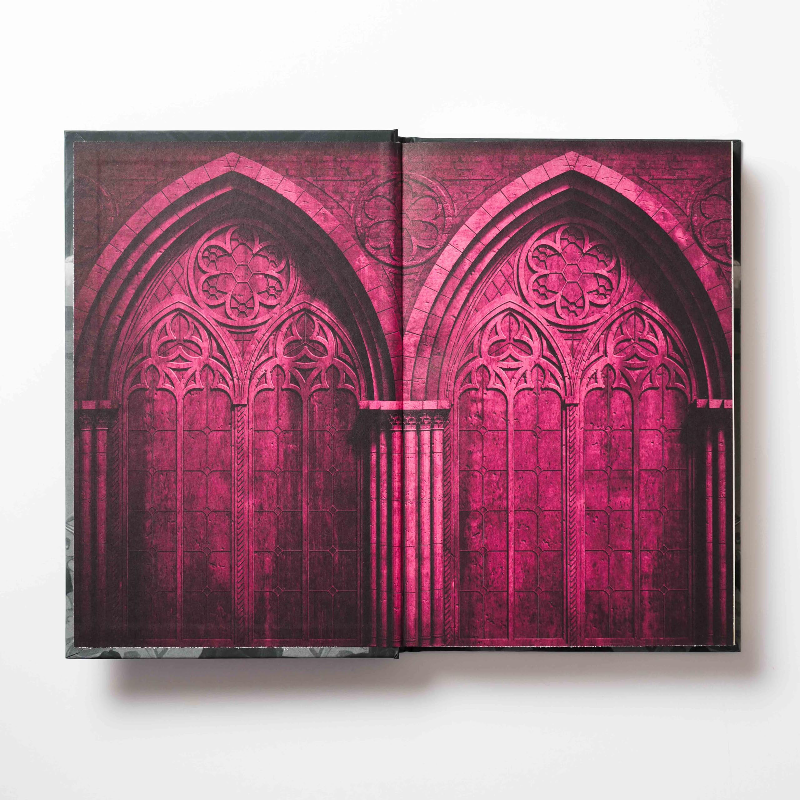 Version 100 – To Speak Online Open book showing a vivid pink Gothic arch stained-glass pattern across both pages.
